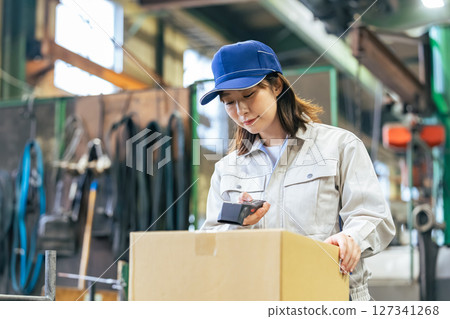 A group of female workers using handheld terminals to manage products in a factory A group of female workers using handheld terminals to manage products in a factory 127341268