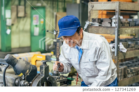 Male worker operating a machine in a factory 127341269