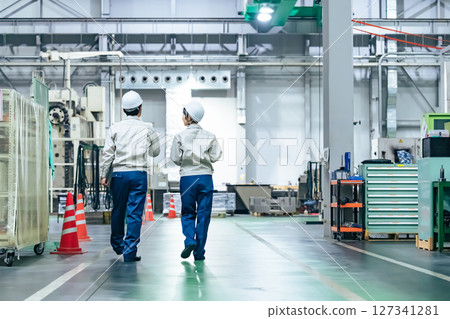 Rear view of a group of workers working in a factory 127341281