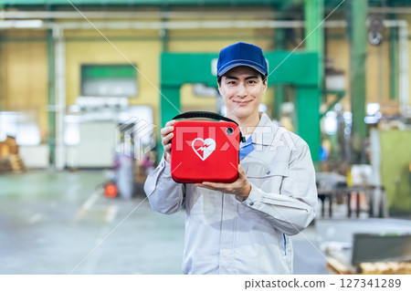 Male worker with AED at factory Male worker with AED at factory 127341289