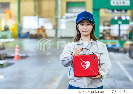 Female worker with AED at factory Female worker with AED at factory 127341293