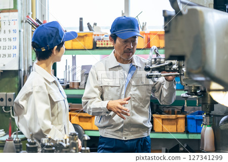 A group of workers operating machine tools in a factory A group of workers operating machine tools in a factory 127341299