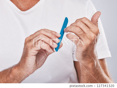 Hands, nail file and grooming with a man in studio on a gray background for beauty while filing his finger nails. Manicure, wellness and cosmetics with a male taking care of his personal hygiene Hands, nail file and grooming with a man in studio on a gray background for beauty while filing his finger nails. Manicure, wellness and cosmetics with a male taking care of his personal hygiene 127341320