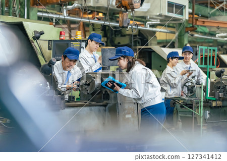A group of workers inspecting a machine using a tablet PC 127341412
