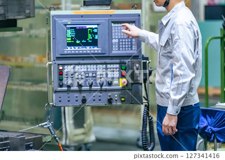 A worker operating a machine on a factory control panel 127341416