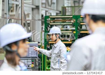 一名男工人在工廠的控制面板上操作機器 127341417