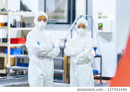 穿著防護衣站在工廠裡的男女工人 穿著防護衣站在工廠裡的男女工人 127341446