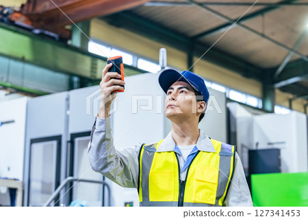 一名工人在工廠使用便攜式測量設備 一名工人在工廠使用便攜式測量設備 127341453