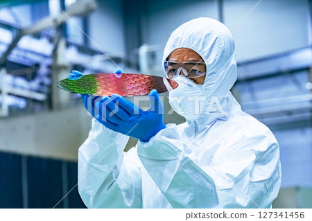 半導體工廠內身穿防護衣的男工人檢查矽片 127341456