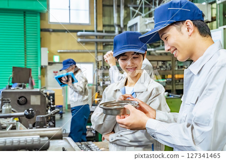 Group of workers operating machines in a factory 127341465
