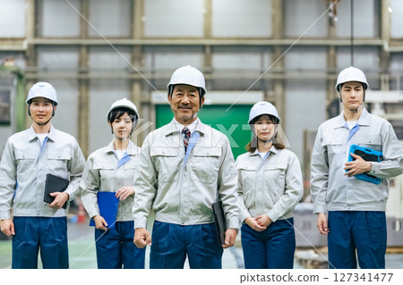 A group of workers standing side by side in a factory 127341477