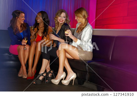 Diversity, women in club and friends party together while drinking champagne, talking on nightclub couch and enjoying happy hour drinks. Young woman, friendship and new year celebration with alcohol 127341910