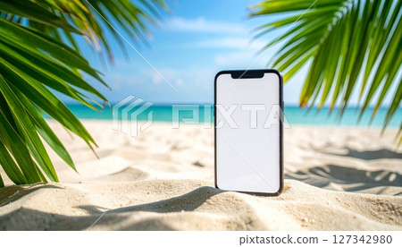 Mobile phone on sandy beach with tropical leaves by the sea 127342980