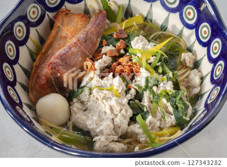 Egg noodles soup served with Crispy pork belly, Fish balls, Minced pork, Cantonese kale. 127343282