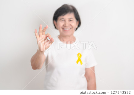 Elderly with Yellow Ribbon for concept of yellow September, Suicide prevention day, Childhood, July Sarcoma, bone cancer Awareness in children month, support survivor. Healthcare and World Cancer day 127343552