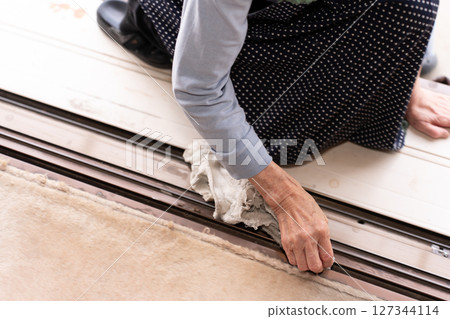 一位老年婦女用抹布清潔鋁製窗框 一位老年婦女用抹布清潔鋁製窗框 127344114