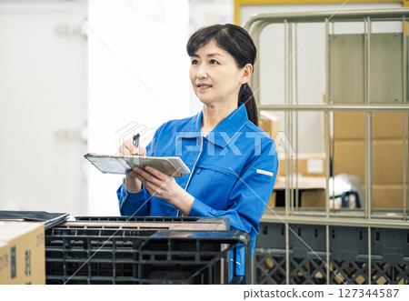 一名 50 多歲的女性在物流倉庫檢查單據 127344587