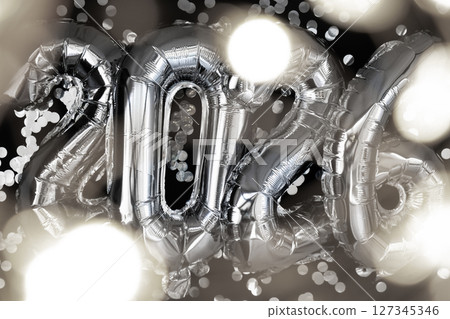 Holiday bokeh garland Happy new year 2026 metallic balloons with confetti on dark black background. Greeting card silver foil balloons numbers Christmas holiday concept. Celebration party 127345346