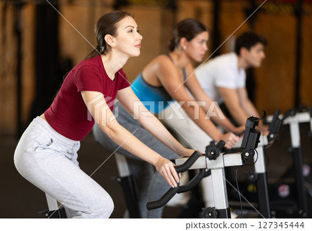 Woman exercising on an exercise bike 127345444