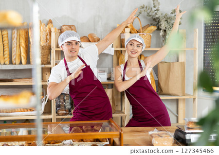 Two enthusiastic young bakers dancing in cozy bakery 127345466
