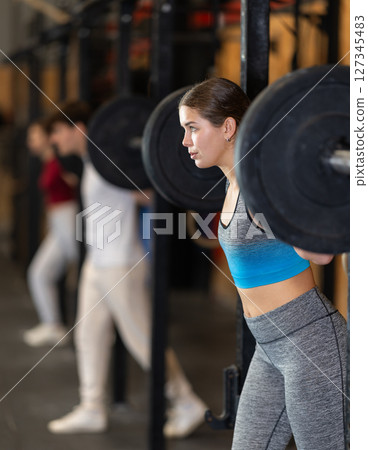 Woman doing strength training with a barbell 127345483