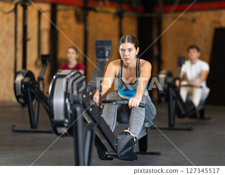 Woman in top exercising on rowing machine Woman in top exercising on rowing machine 127345517