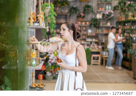 Woman in white dress buys candles and other gifts for family and friends in gift shop 127345687