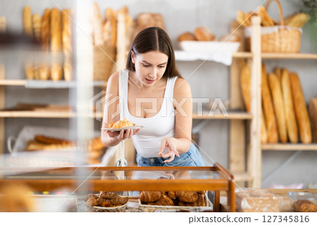 Young female buyer choosing croissants in bakery Young female buyer choosing croissants in bakery 127345816