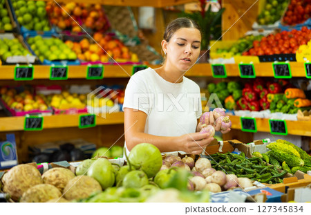 Portrait of girl customer buying radish at grocery shop 127345834