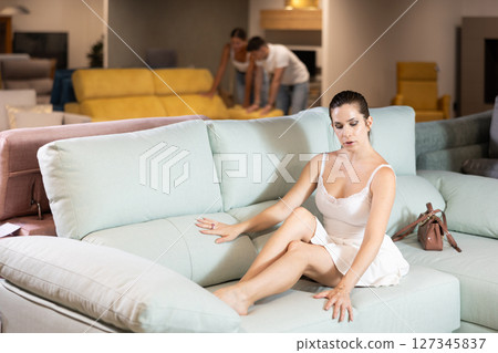 Young woman choosing convenient sofa in furniture shop Young woman choosing convenient sofa in furniture shop 127345837