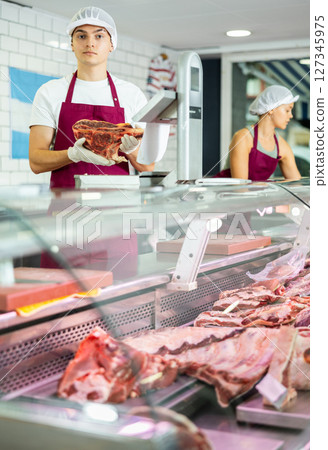 Male meat vendor provides selection 127345975