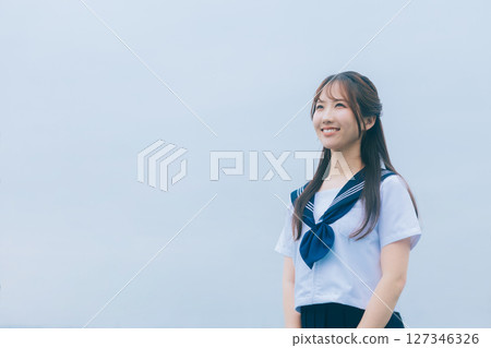 A high school girl in summer clothes looking up at the sky 127346326