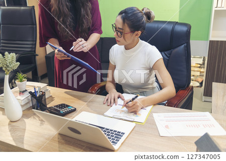 Diversity Two Businesswoman working together in office desk. Two cuacasian asian women look at financial report document as partner teamwork. Team leader coworker brainstorming executive entrepreneur 127347005