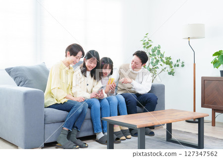 父母和孩子在客廳裡使用智能手機 父母和孩子在客廳裡使用智能手機 127347562