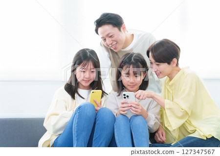 Parents and children using smartphones in the living room Parents and children using smartphones in the living room 127347567