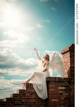 An angel reaching for the sky. A prayer wrapped in light. 127347944