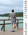 Young man standing near lake, view from back. Recreation in nature concept Young man standing near lake, view from back. Recreation in nature concept 127348148