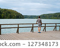 Young man standing near lake, view from back. Recreation in nature concept Young man standing near lake, view from back. Recreation in nature concept 127348173