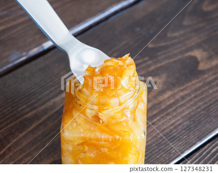 橘子醬是將柑橘皮和水果煮至甜而製成的。圖中人物正在用湯匙舀果醬。 127348231