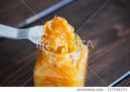 將柑橘皮和水果甜甜地燉煮而成的果醬。用湯匙舀出果醬。 127348233