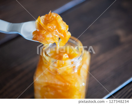 將柑橘皮和水果甜甜地燉煮而成的果醬。用湯匙舀出果醬。 127348234