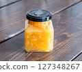 A glass jar filled with marmalade jam made by sweetly stewing citrus peels and fruits. 127348267