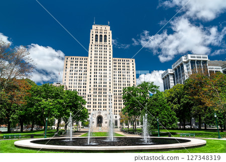 In Albany, United States, the art deco State Office Building towers behind park lawns and splashing fountains under a bright blue sky In Albany, United States, the art deco State Office Building towers behind park lawns and splashing fountains under a bright blue sky 127348319