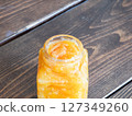 A glass jar containing marmalade jam made by sweetly stewing citrus peels and fruits. 127349260