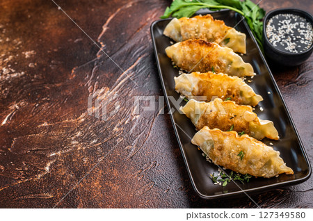 Fried Korean Dumplings on plate with sauce, Dumplings with shrimps and vegetables. brown background. top view Fried Korean Dumplings on plate with sauce, Dumplings with shrimps and vegetables. brown background. top view 127349580