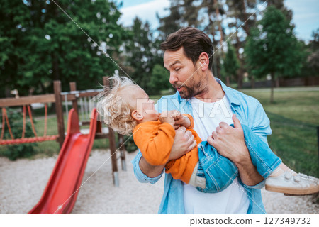 Father playing with toddler son outdoors in park 127349732