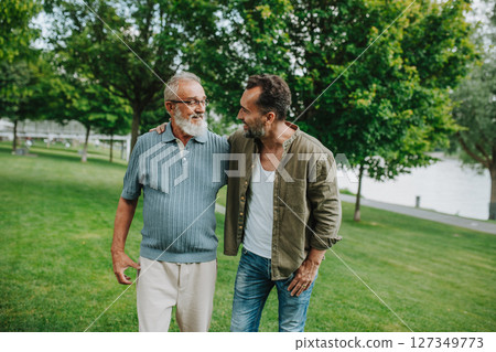 Senior dad and middle-aged son enjoying peaceful walk in park. Senior dad and middle-aged son enjoying peaceful walk in park. 127349773