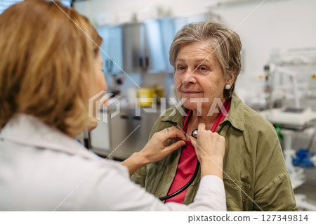 Geriatrician doctor examining elderly patient with stethoscope. 127349814
