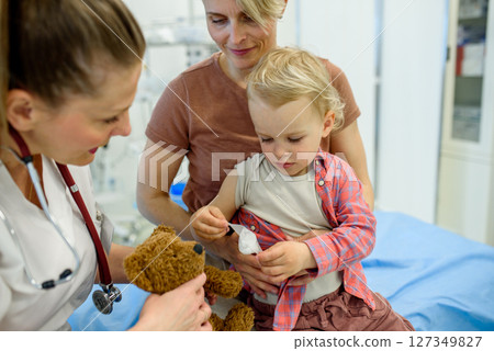 Doctor and young toddler patient treat a teddy bear. 127349827
