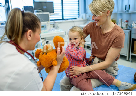 Female pediatrician comforting little boy with teddy bear. 127349841